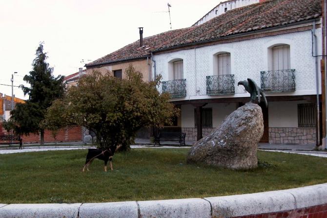 Foto: Perrita ladrando a la escultura de bronce de un águila - Aguílafuente (Segovia), España