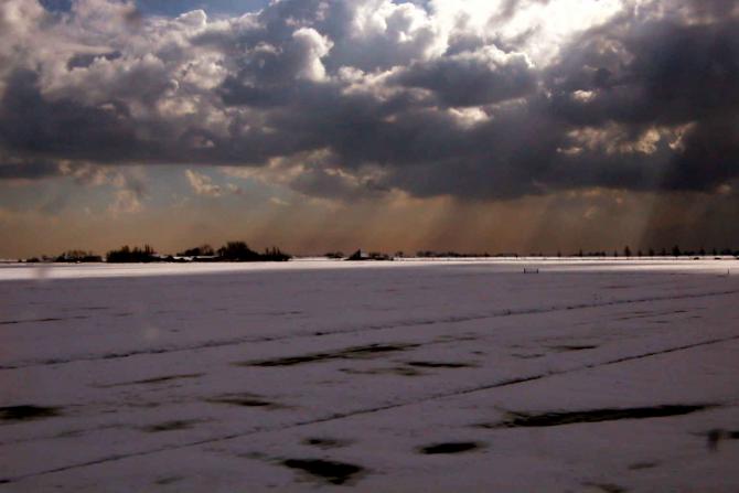 Foto: Sobre la localidad nevada llegan filtrados por las nubes los rayos de sol - Volendam (North Holland), Países Bajos