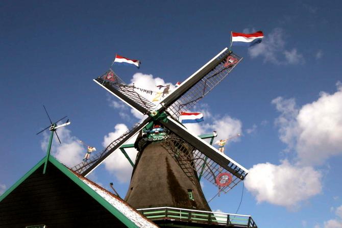 Foto: Bello molino con banderas en las aspas - Zaandam (North Holland), Países Bajos